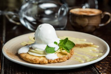 Dondurma kepçesi, beyaz tabakta meyve şurubuyla süslenmiş masaya yakın plan.