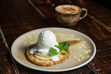 Dondurma kepçesi, beyaz tabakta meyve şurubuyla süslenmiş masaya yakın plan.