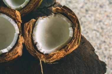 Ahşap bir masada kırılmış hindistan cevizleri ve yakın avuçlarında yapraklar.