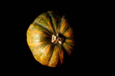 Taze bir balkabağı, tek bir ışık kaynağı, siyah bir arkaplanda.