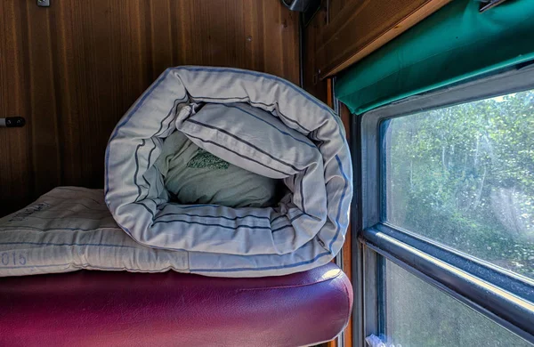 Bir rulo, kalabalık yatak, demiryolu Araç bölmesinin üst rafta yatıyor. Rusya. Sokaklarda bir pencere var.