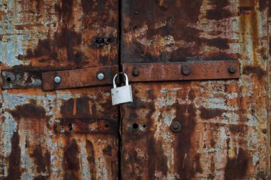 Eski demir kapı yeni bir asma kilide kapatıldı. Kapılar paslanmış. Görünür cıvata başları - paslı ve gümüş. Geçmişi. Doku.