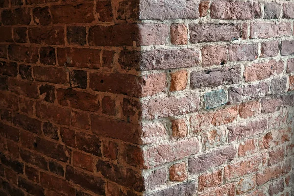 The corner of the old brick wall is lit on one side. The second side is in the shade. The surface of the brick is rough. Background. Texture.