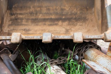 Kazı kovasının içine bir göz at. Çelik bir tabanı ve kaba dişleri var. Her yerde metal parçalar, borular ve zincir var. Geçmişi. Yakın plan..