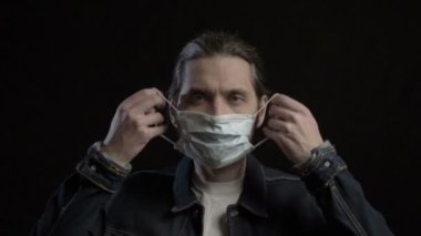 Adam antivirüs için yüzüne maske takıyor ve ileriye bakıyor.