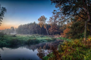Sis, Güneş doğmadan önce nehirde. Bulutlar güneşin ilk ışınları gelen sıcak bir parlaklık.