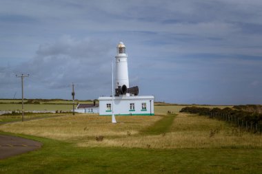 Yeşil çayırlar arasında tarihi bir deniz feneri bulunan Galler kıyıları.