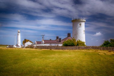 Yeşil çayırlar arasında tarihi bir deniz feneri bulunan Galler kıyıları.