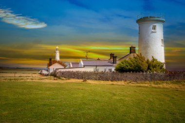 Yeşil çayırlar arasında tarihi bir deniz feneri bulunan Galler kıyıları.