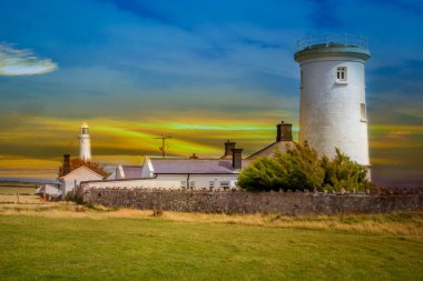 Yeşil çayırlar arasında tarihi bir deniz feneri bulunan Galler kıyıları.