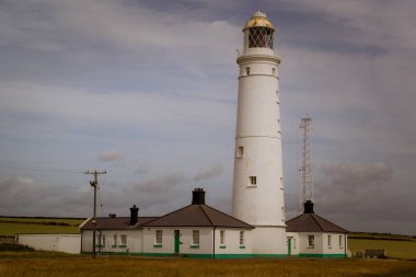 Yeşil çayırlar arasında tarihi bir deniz feneri bulunan Galler kıyıları.