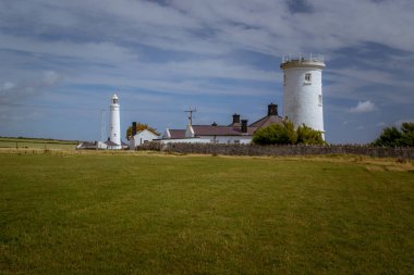 Yeşil çayırlar arasında tarihi bir deniz feneri bulunan Galler kıyıları.