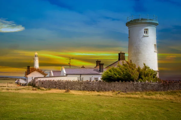 Yeşil çayırlar arasında tarihi bir deniz feneri bulunan Galler kıyıları.
