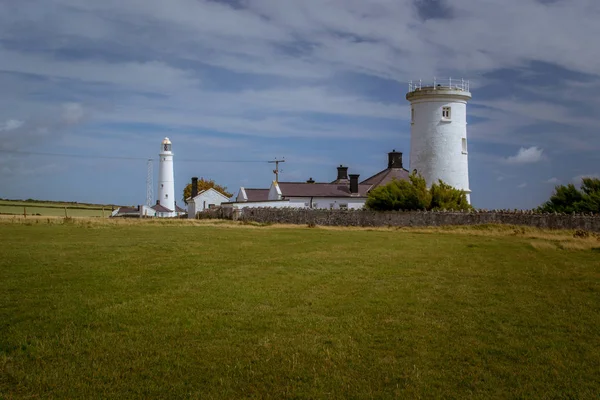 Yeşil çayırlar arasında tarihi bir deniz feneri bulunan Galler kıyıları.