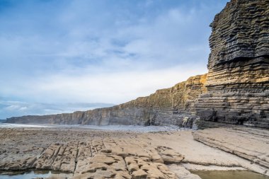 Galler - günbatımında kıyıda yaban kayalıklar ve kayalık kıyılar.