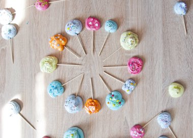 Saat meringues şeklinde. beze şeker çubuk üzerinde. renkli swiss veya pastel tonları içinde ahşap arka plan üzerinde İtalyan tarifi tatlılar. doğum günü partisi zaman ve tatil kutlaması. düz yatıyordu tatlı zemin.