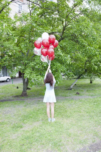 到达天空 在自然绿色背景上拿着气球的顽皮的年轻女子的全长镜头 — 图库照片