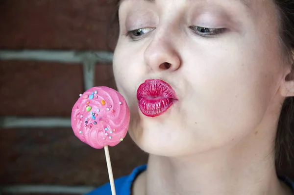 Beauty fashion model girl taking sweet meringue lollipop. Funny joyful Vogue styled woman choosing sweet on brick background. Diet, dieting concept. kiss and love