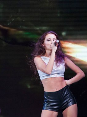 sahnede seksi şarkıcı. kadın moda deri şort ve gümüş top. kadın slim göbek mikrofonla şarkı ve tabaklanmış deri. Kızın smokey makyaj ve esmer saç var. müzik ve ses talant.
