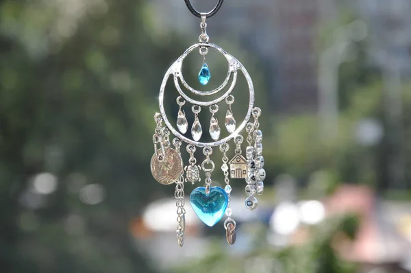 Some believe in luck. Name amulet for good luck. Luck amulet hung out outdoor. Silver amulet with gems and pendants. Believing in magic protecting the holder of amulet. Jewelry charm or talisman.