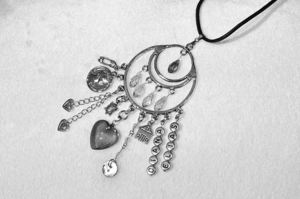 Believing in magic protecting the holder of amulet. Jewelry charm or talisman. Name amulet for good luck. Luck amulet on textile background. Silver amulet with gems and pendants. Repelling bad luck.