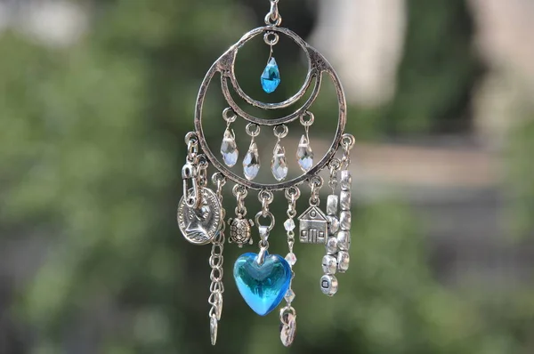 Magical power. Name amulet for good luck. Silver amulet with gems and pendants. Luck amulet hung out outdoor. Believing in magic protecting the holder of amulet. Jewelry charm or talisman.