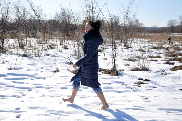 漂亮可爱的年轻黑发女孩在蓝色冬衣与毛皮阳光寒冷的冬日在自然白色背景赤脚走在雪 — 图库照片