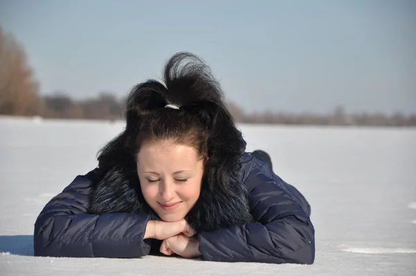 漂亮可爱的年轻黑发女孩在蓝色冬衣与毛皮阳光寒冷的冬天天在自然白色背景铺设在雪 — 图库照片