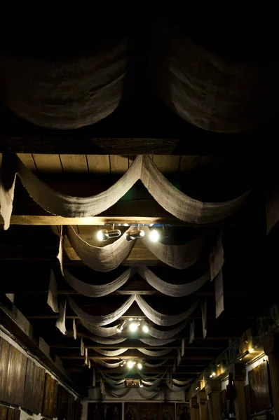 Showing off the architectural features of the ceiling. Decorative old ceiling with drapes. Ceiling drapery. Wood beam ceiling with draped textile. Classic overhead interior surface.