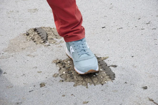 Poo happens. Male foot in sport shoe on tire track over animal excrement. Foot stepped on piece of dry cow poop. Rural life and active lifestyle.