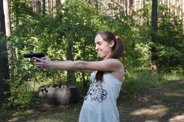 Woman with weapon. Girl shooting from gun. Kill and war. Gun in hand of shooter. Hunting and education outdoor in forest., aim and success