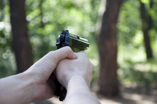 Цель и оружие, пистолет в руке стрелка. Убийство и война. Охота и образование на открытом воздухе в лесу. стрельба из пистолета., цель и успех
