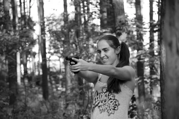 Woman with weapon. Kill and war. Gun in hand of shooter. Hunting and education outdoor in forest. Girl shooting from gun., black and white, aim and success