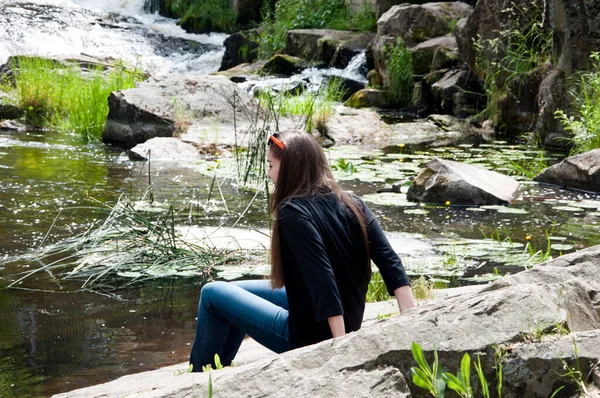 girl relax on stony coast. water and stones. waterfall nature. flowing running water of waterfall. beautiful places. travel and wanderlust. summer vacation and holiday. rocky terrain.