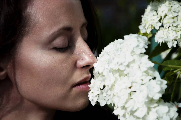 woman smelling beautiful hydrangea bouquet. Countryside lifestyle gardening. Fashionable girl with flowers. perfect skin. organic cosmetic care. natural makeup. spa and beauty salon. spring allergic.