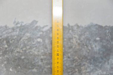 Ölçme aleti. Onarım ve inşaatta kullanılan seviye ölçüm ekipmanları. Ölçüm aleti. Metal profil çizgisi üzerinde inşaat aracı. Grange çimento duvar arka planında sarı bant ölçüsü.