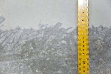 Ölçüm aleti. Metal profil çizgisi üzerinde inşaat aracı. Çimento arka planında sarı şerit var. kopyalama alanı. Ölçme aleti. Onarım ve inşaatta kullanılan seviye ölçüm ekipmanları.