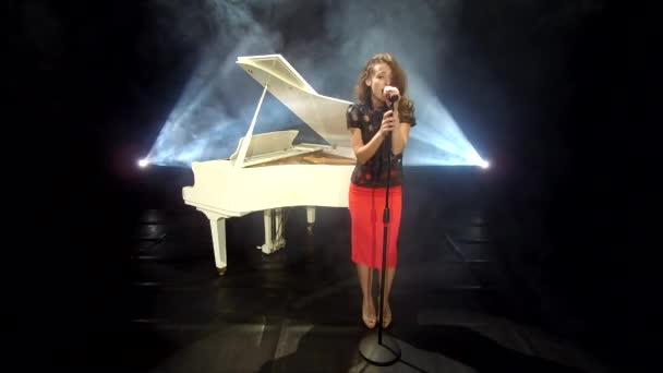 复古女歌手在舞台上用麦克风演唱爵士乐 配上彩灯和白色钢琴 — 图库视频影像