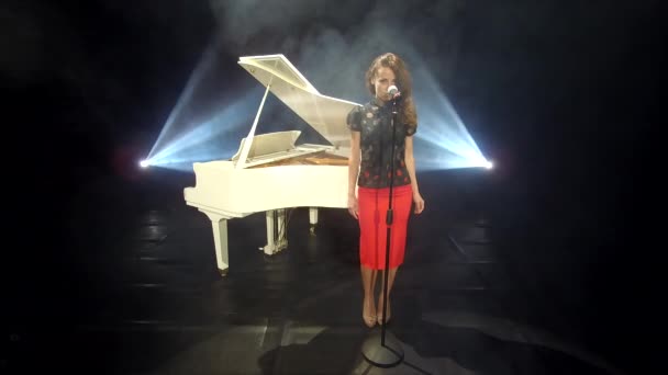复古女歌手在舞台上用麦克风演唱爵士乐 配上彩灯和白色钢琴 — 图库视频影像