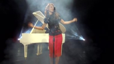 Sahnede beyaz piyano forte ile retro şarkıcısı şarkı söylerken duygularını ifade eder, müzik.