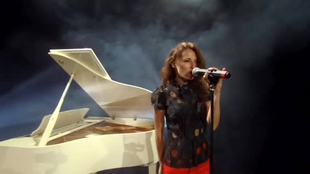 性感性感的性感女歌手在古典白钢琴前用麦克风演唱歌曲 声乐俱备 — 图库视频影像