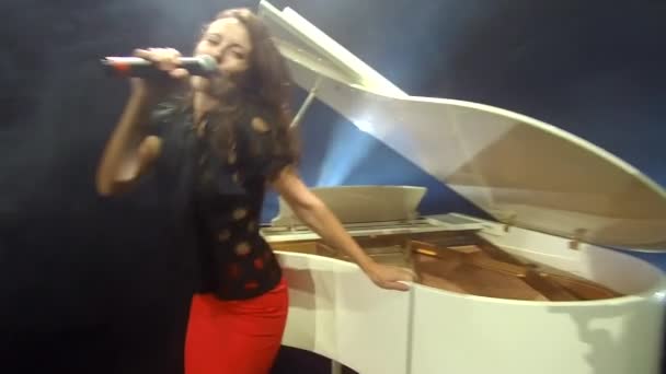 用麦克风唱歌 流行歌星专业现场主唱声乐表演 卡拉Ok 有麦克风的性感歌手 唱一首歌 性感女歌手 带着白色钢琴的复古歌手登上舞台 — 图库视频影像