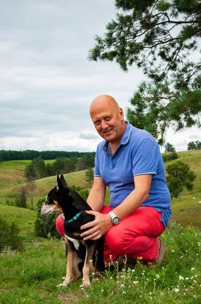 Дружба и единение. Пейзаж портрет человека и домашней собаки на открытом воздухе. Домашнее животное для мужчины. Путешествие с домашним животным. Собака. Человек и собачий друг. Человек играет в собаку.