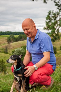 Yürüyüş ve antrenman. Doğada köpekli bir adam, sevgisini gösteriyor. Arkadaşlık ve birliktelik. Açık havada insan ve evcil köpeğin manzara portresi. İnsanın evcil hayvan arkadaşı. Köpekle kamp yapmak..