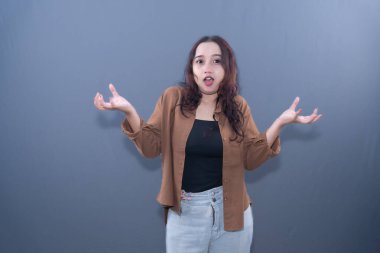 Genç bir kadın ellerini kaldırarak şaşkınlık ya da belirsizlik gösterir.