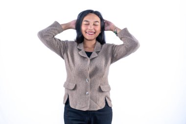 Ceketli gülümseyen kadın, elleri başının arkasında, mutluluktan gözleri kapalı beyaz arka planda..