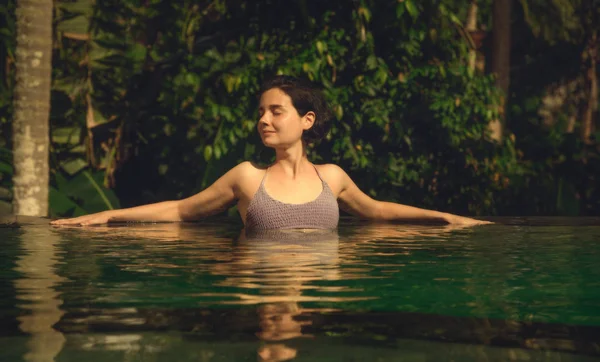 The girl in the infinity pool. Pool in the jungle. Holidays in Bali. The girl is tanning. Relax.