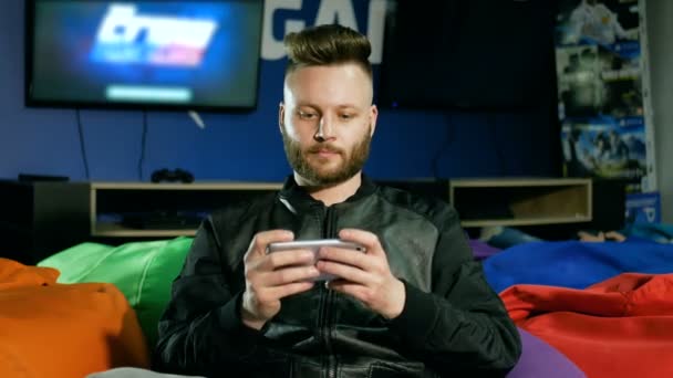 Barbudo cara que joga jogos em um smartphone é oferecido para tomar um joystick e ele se recusa . — Vídeo de Stock