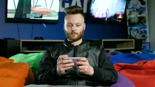 O cara barbudo que joga em um smartphone é oferecido para pegar um joystick e ele o pega e o telefone joga fora — Vídeo de Stock