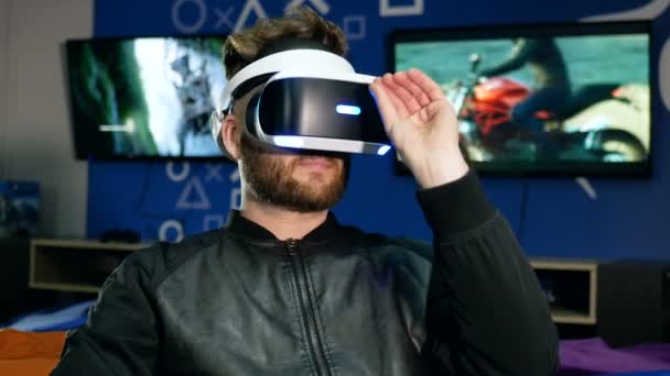 Mladý muž vnímá objekt ve virtuální realitě prostřednictvím speciálních brýlí. Vousatý muž zvedne helmu pro hru a je velmi zapůsobilo s incident. — Stock video